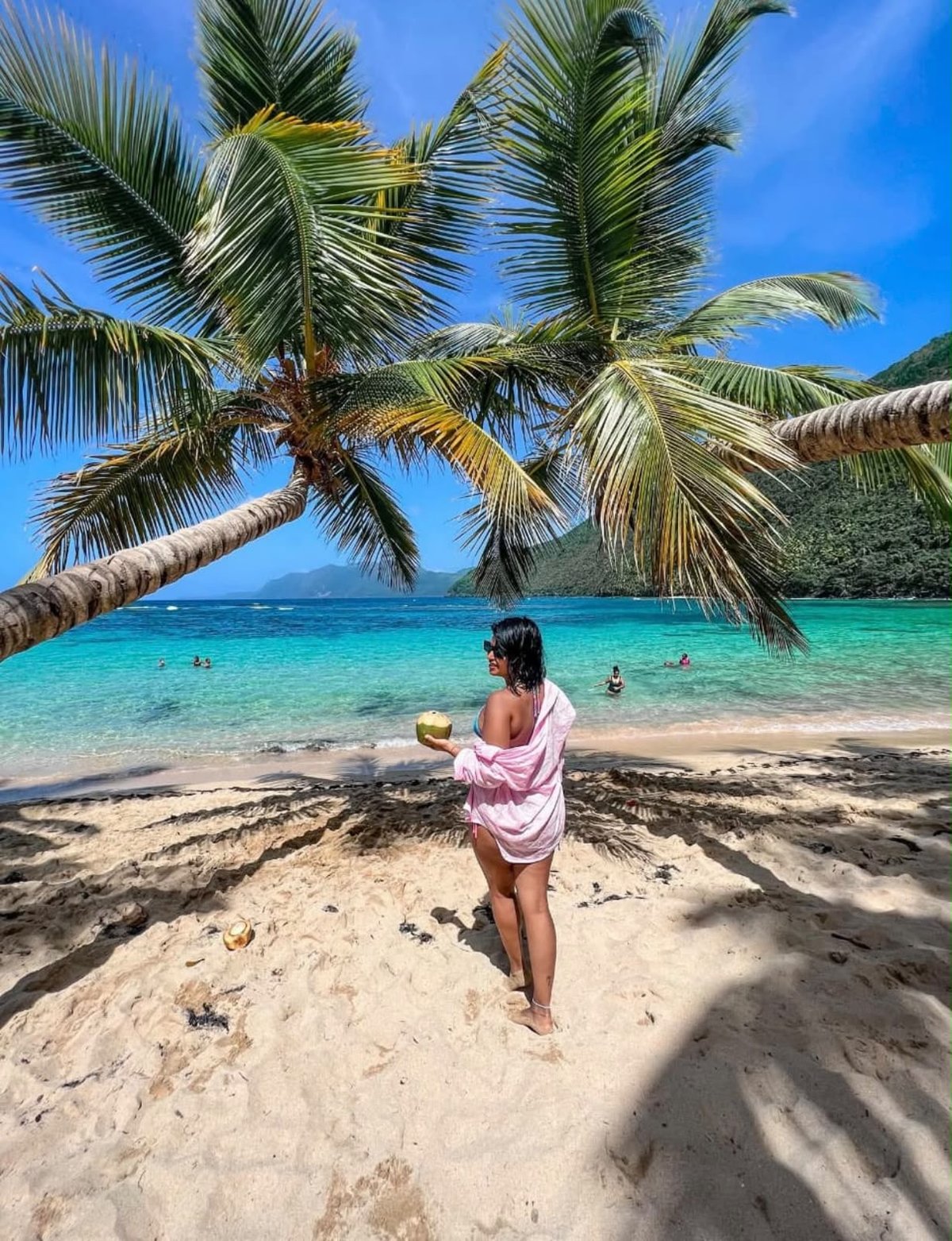 Guest with a coconut on a palm-lined beach